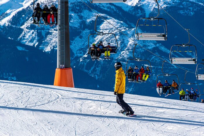 vacanze sulla neve - un impianto di risalita con tanta gente seduta, uno sciatore sulla pista da sci in montagna