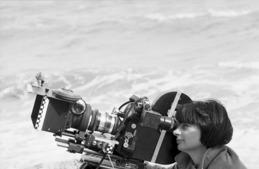 Agnes Varda in una foto in bianco e nero della gioventù scatto dietro la cinepresa di profilo