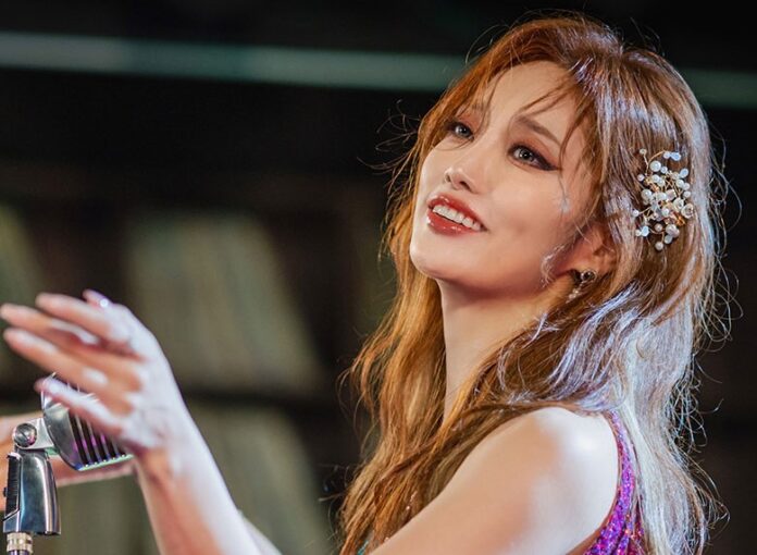 marchio bossa - la cantante coreana Ryu Zee Su in primo piano, sorridente, con i capelli rossi. Davanti a lei un microfono vintage di metallo cromato