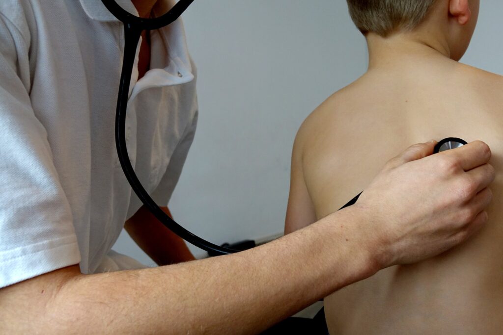 Emergenza smog inquinamento - un dottore sta visitando un bambino con uno stetoscopio posto sulla schienma del bimbo