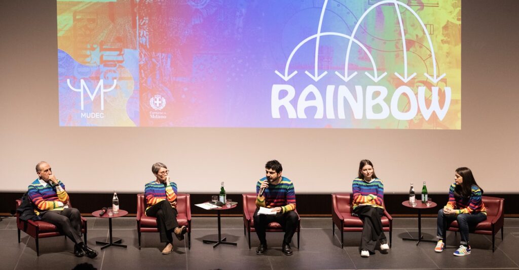 immagini conferenza stampa rainbow con persone seduta con maglie carcobaleno