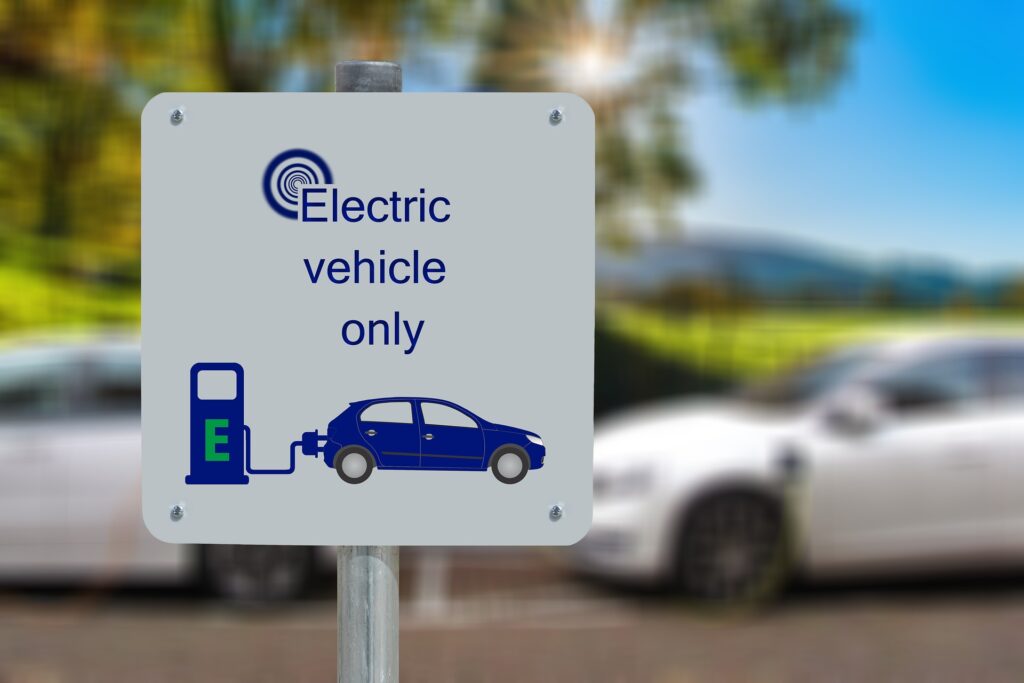 colonnine per auto elettriche - il cartello che indica il punto di ricarica con una macchina blu e una presa elettrica blu attaccata ad una colonnina blu con la lettera "E" verde