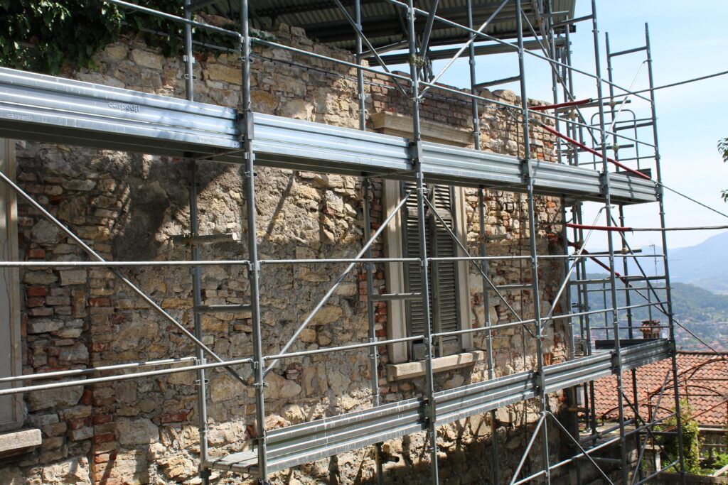 ristrutturazioni - dei ponteggi montati sulla facciata di una casa in pietra