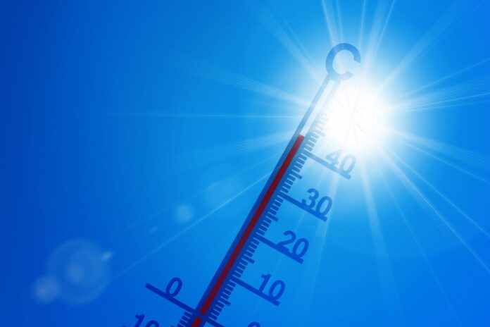 caldo estremo - un termometro per temperature clima puntato verso un cielo blu dove splende il sole