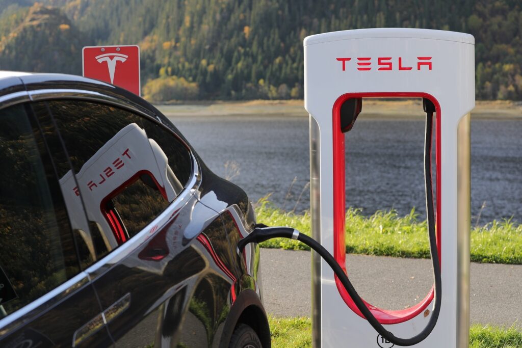 auto elettriche in ricarica ad una colonnina binca con la scritta rossa "Tesla"