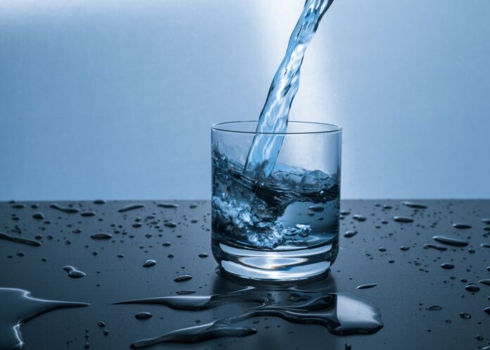 emergenza ambientale: dell'acqua che si sta versando in un bocchiere appoggiato su una superficie bagnata. L'immagine ha colori tra il bianco e l'azzurro