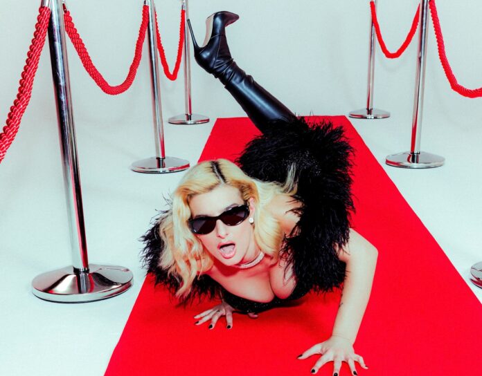 attrazione fatale - beatrice quinta, vestita di nero con gli occhiali da sole, è distesa su un tappeto rosso