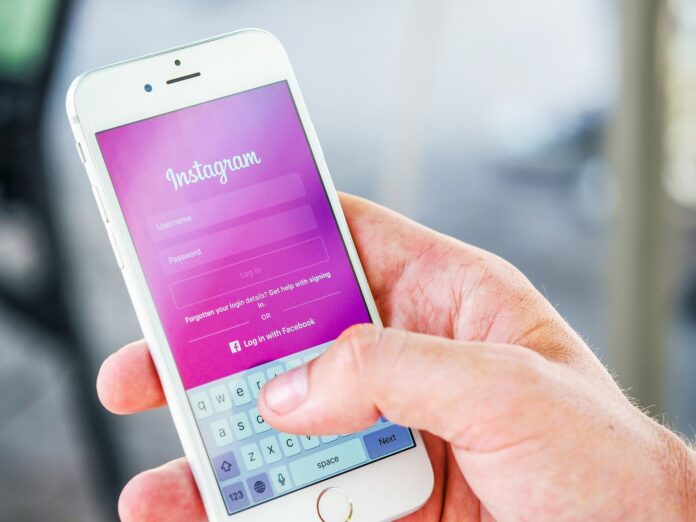 Post sui social Meta - nella foto una donna tiene in mano un cellulare e sulla schermata c'è la home di Instagram