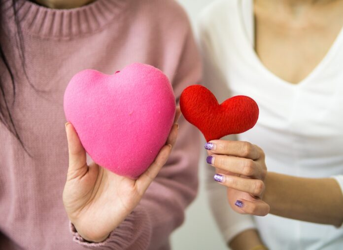 donazione organi trapianto - due donne, un avicina all'atra tengono tra le mani due cuori, uno rosa e uno rosso