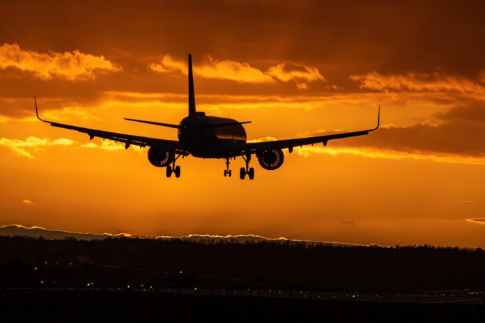 voli notturni e inquinamento - un aereo in volo verso un tramonto