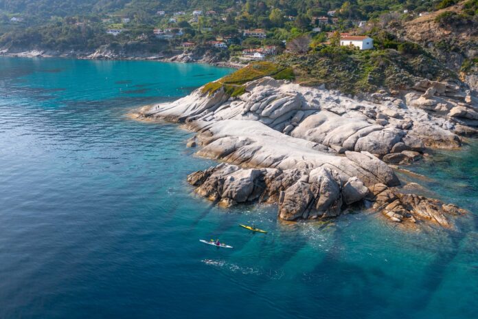 coste dell'isola d'elba con mare trasparente e turchino scogliere binache e kayak sul mare