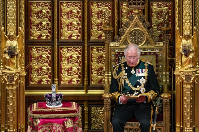 carlo nel 2022 mentre legge un messaggio della regina seduto al trono con accanto la corona