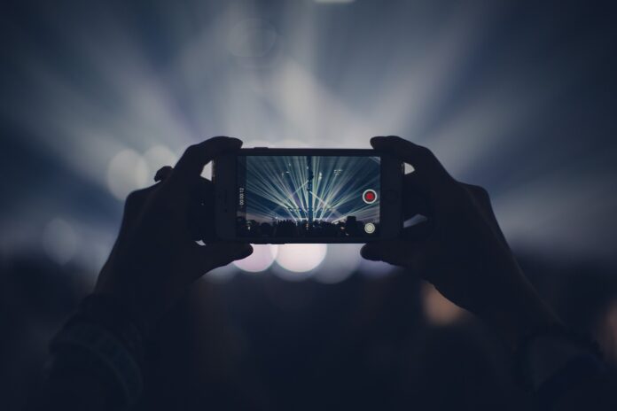 astimusica - nella foto due mani sostengono uno smartphone durante un concerto