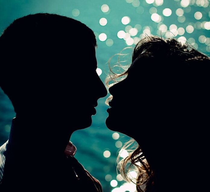 viagra - un uomo e una donna completamente in ombrastanno per baciarsi e dietro lo sfondo è blu con glitter
