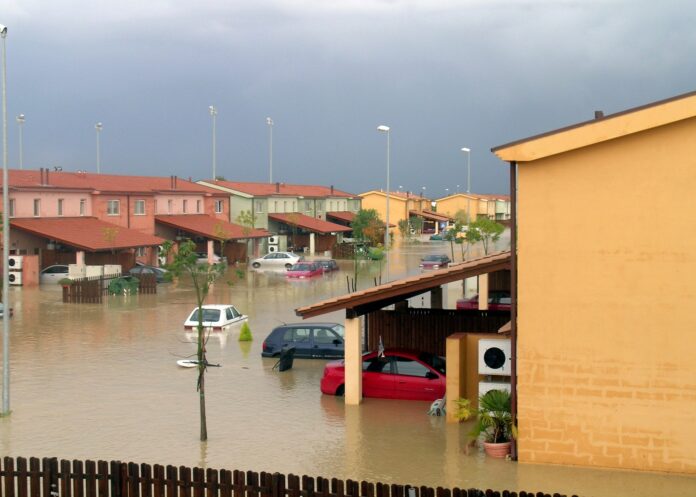 Alluvione a Senigallia - delle villette a schiera per metà sommerse da un fiume d'acqua con macchine galleggianti