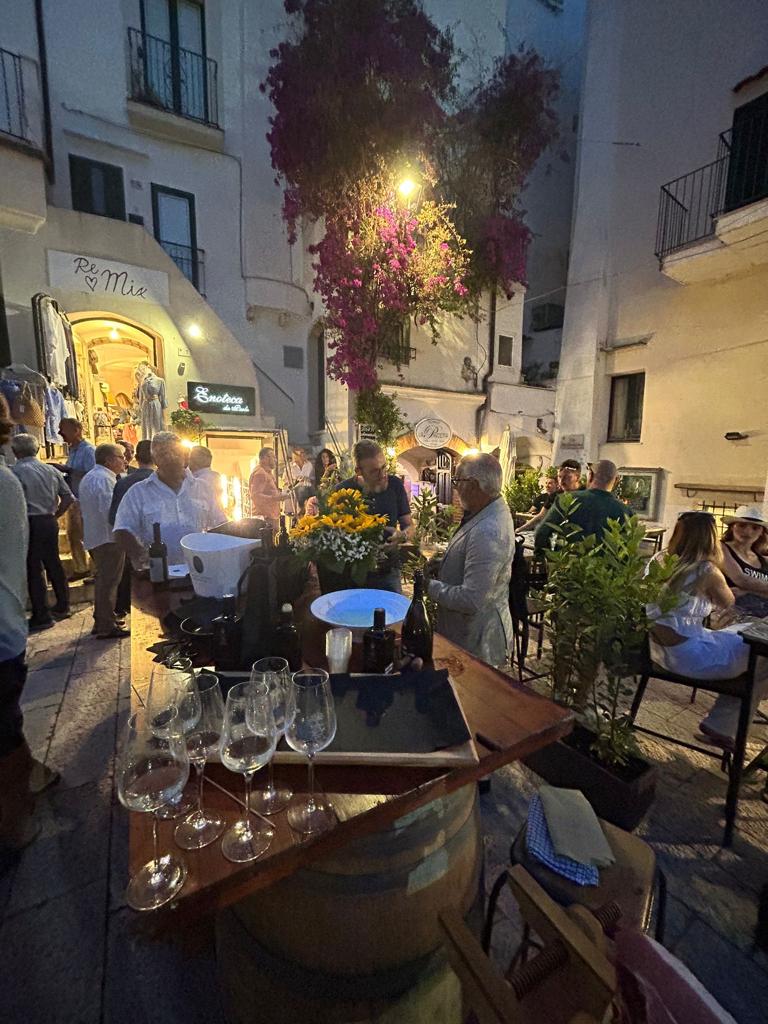 Sperlonga - delle persone in piazza mangiano e bevono in piedi lungo un tavolo