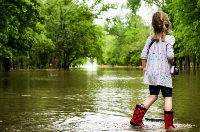 alluvione in Romagna, una bambina con stivaletti rossi a pois neri saltella nell'acqua