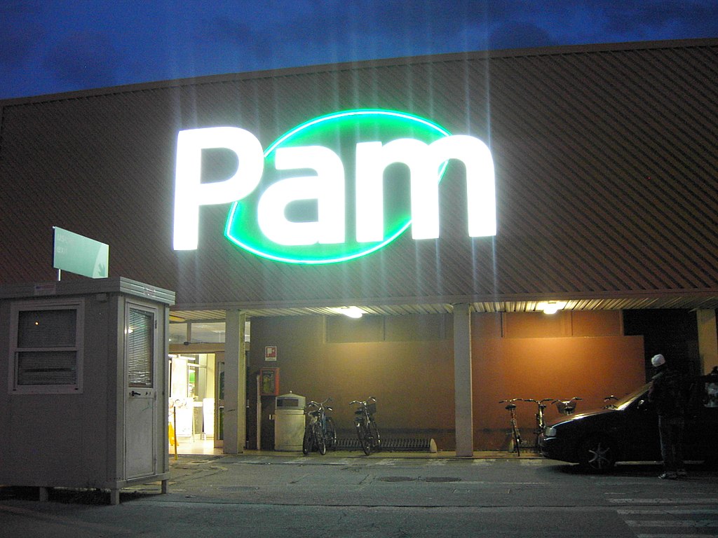 supermercati pam la vista dell'ingresso, di notte, con la scritta bianca davanti ad una foglia verde