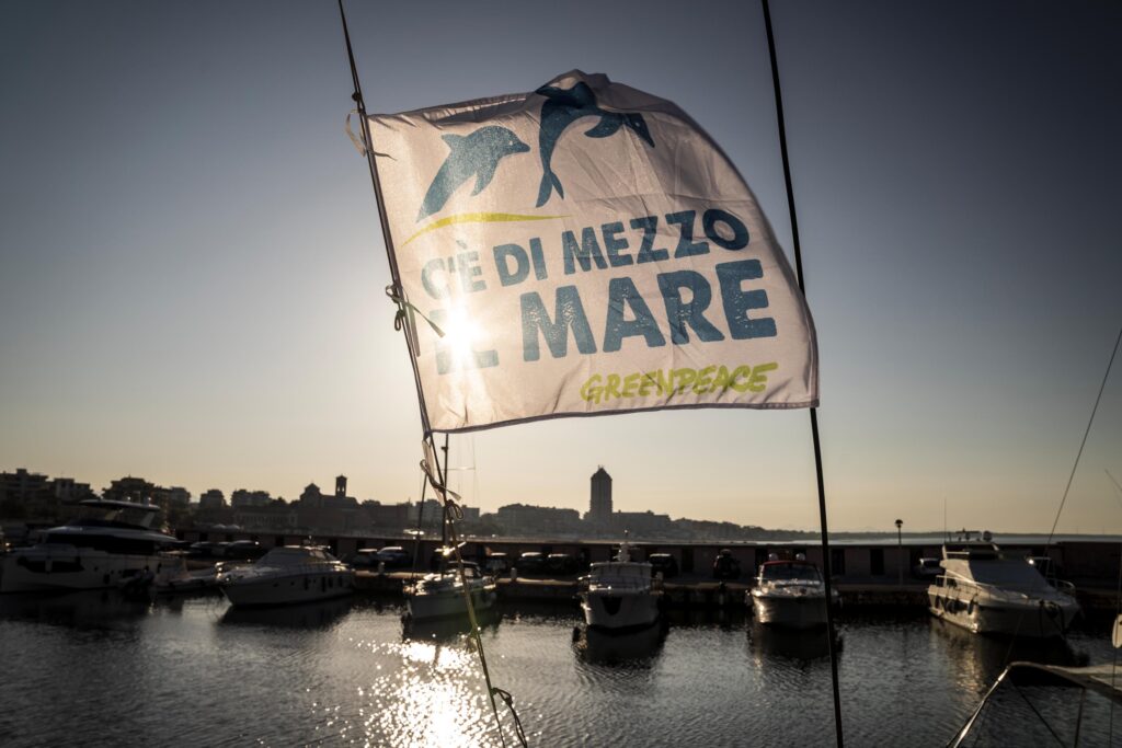  un telone con la scritta "C'è di mezzo il mare" in un porto con delle barche