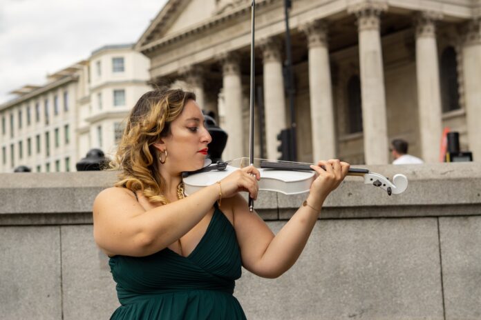 beatrice limonti indossa un abito nero da sera ed è intenta a suonare un violino bianco