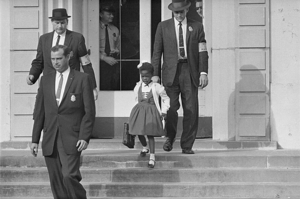 foto di repertorio, polizziotti scortano fuori da una scuola una bambina di colore
