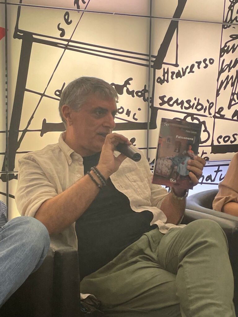 Fabio Ceraulo seduto mentre presenta il suo libro che tiene in mano