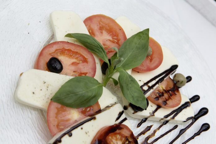 un piatto di pomodori tagliati a fette con mozzarella tagliata a fette e cosparsi di aceto balsamico