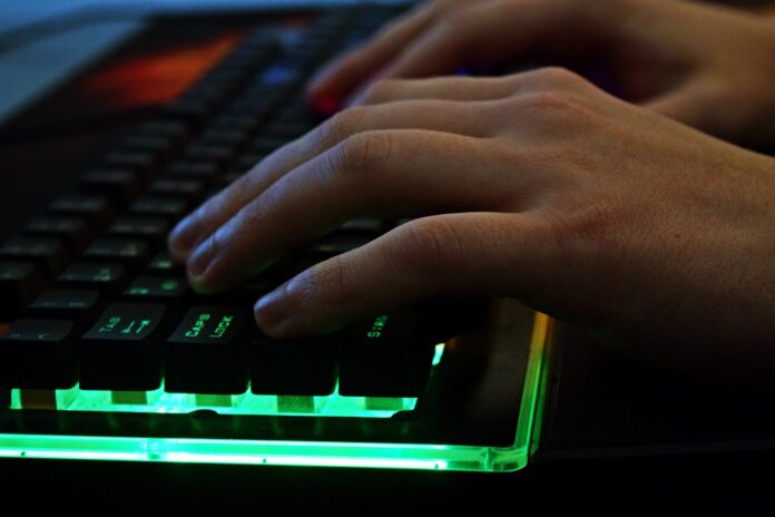 Pornhub - nella foto il primo piano di due mani di uomo che digitano su una tastiera illuminata da luci led verdi