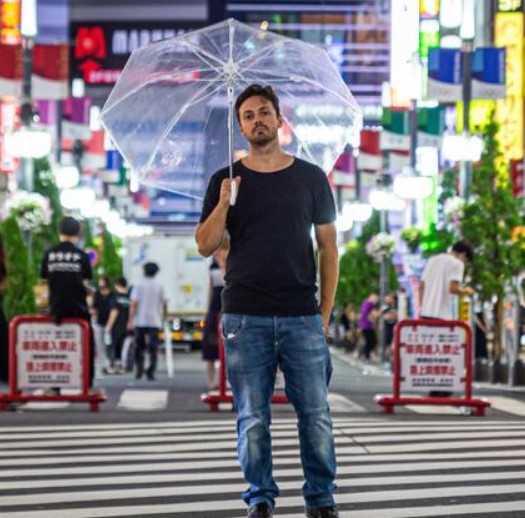 tommaso scotti l'autore del libro i diavoli di tokyo ovest fotografato sotto un ombrello trasaprente in giappone