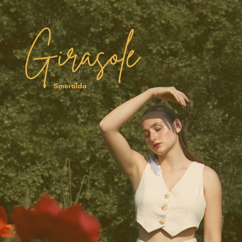 girasole - smeralda in promo piano indossa un gilet chiaro e ha la mano destra appoggiata sulla testa