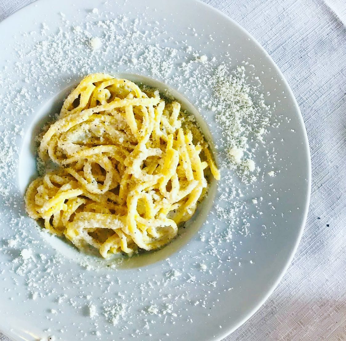 nella foto un piatto a forma di "cappello da prete" con dentro una porzione di pasta alla cacio e pepe