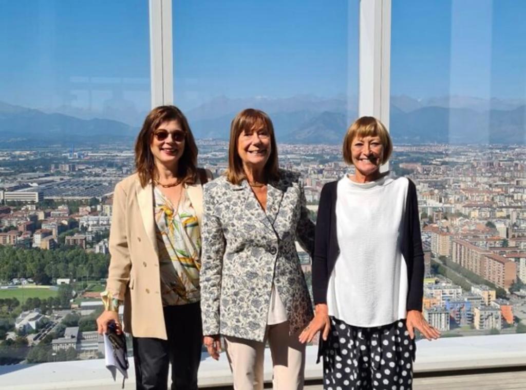 Biblioteche BI.TO - tre donne, le tre assessore, in posa in foto istituzionale. Dietro di loro una grande finestra con vista panoramica su Torino. Da sinistra a destra, la prima donna indossa pantaloni scura e giacca beige. Ha lunghi capelli neri. Al centro la donna veste pantalone beige e giacca a fiori chiaa, ha lunghi cpaelli castai. A destra la donna indossa maglia bianca, golf nero e pantaloni neri a pois e ha capelli biondi a caschetto