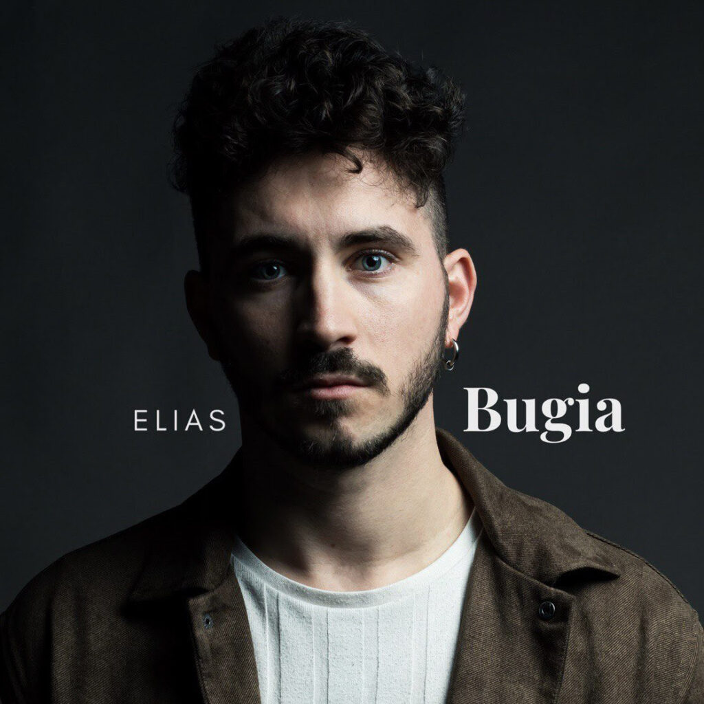 bugie - elias in primo piano nella copertina del nuovo singolo. ha larcae capelli scuri e corti, indossa una t shirt chiara e un giubbotto scuro