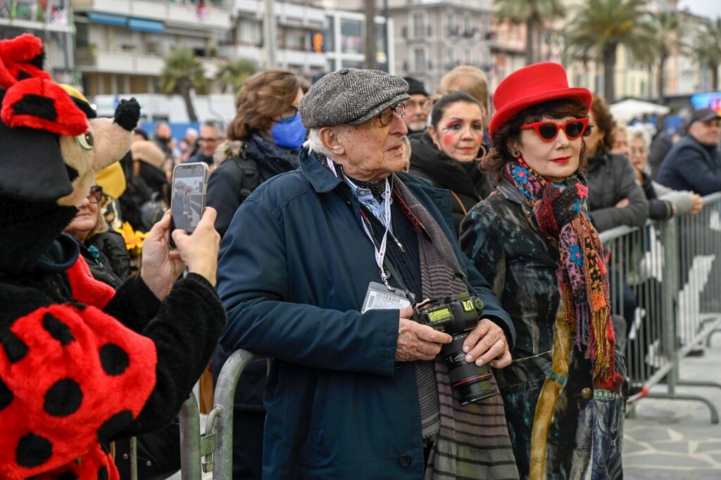 Elisabetta Sgarbi - un uomo anzioano con coppola e cappotto e una donna di mezza età con cappotto e cappellino rosso