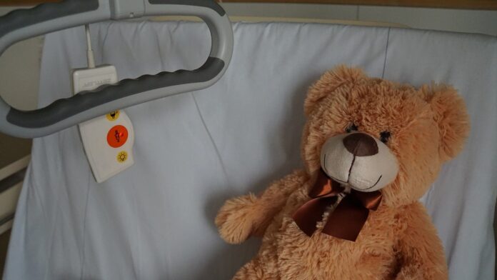 pediatria - un orsetto di peluches coricato in un letto di ospedale