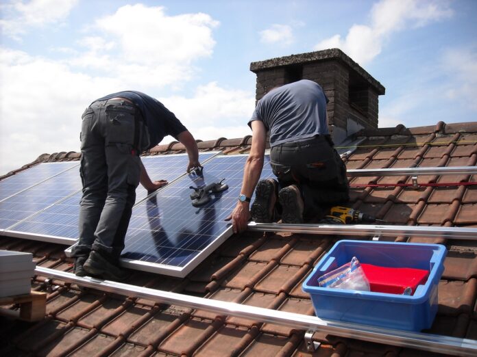 pannelli solari o fotovoltaici durante un'installazione di due uomini che lavorano su un tetto