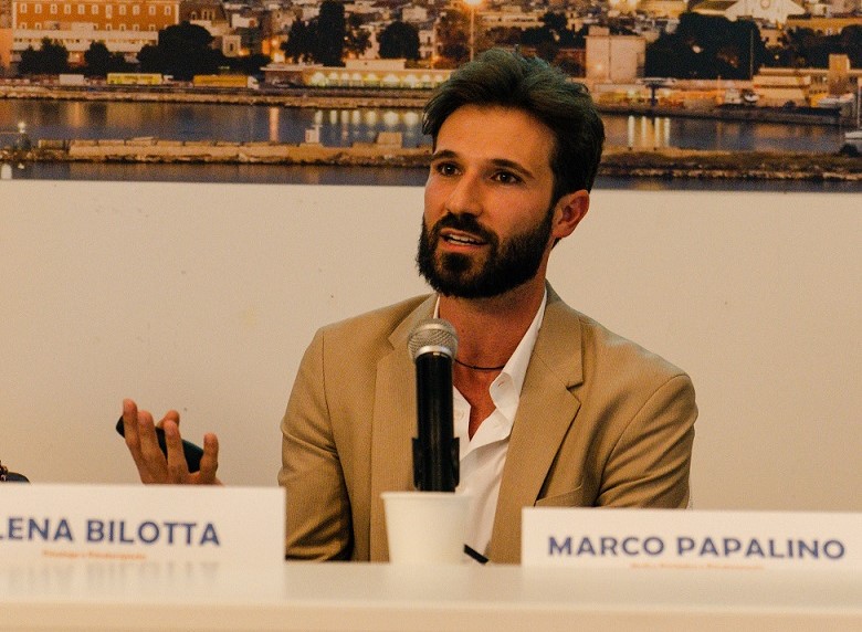 Marco papalino seduto al tavolo di una conferenza sta parlando