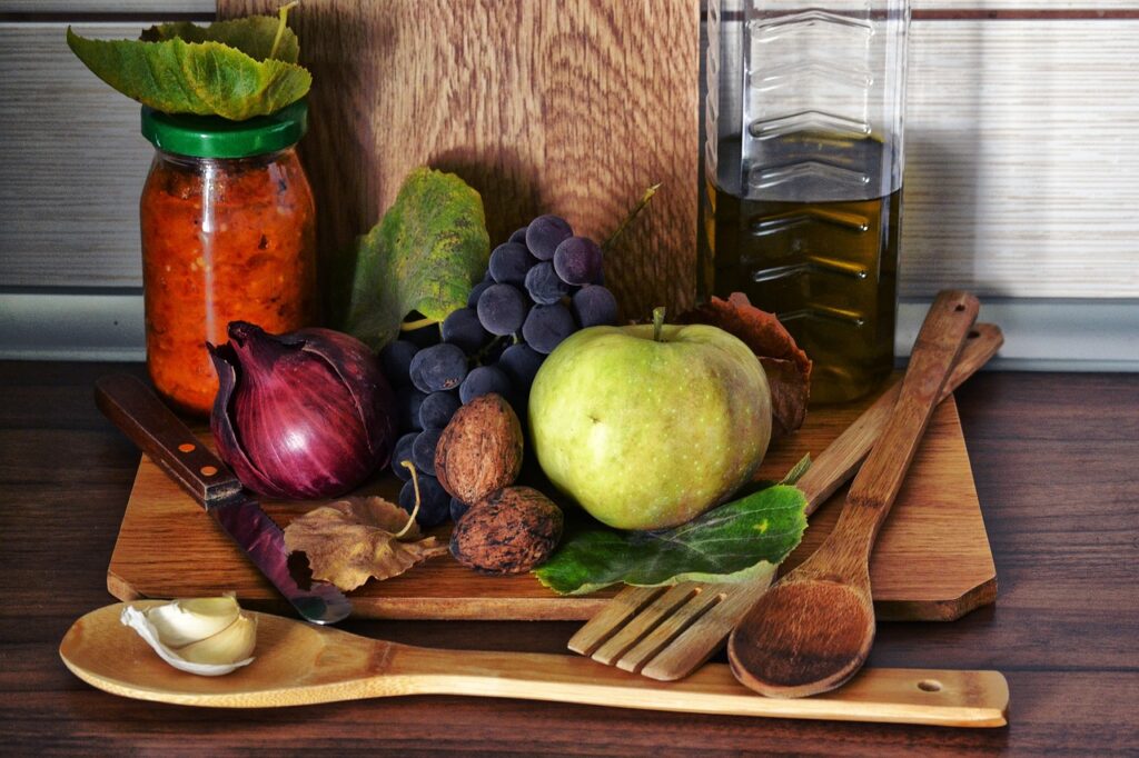  frutta e verdura disposta ordinatamente in un acomposizione con dietro un tagliere di legno e davanti un cucchiaio e una forchetta di legno