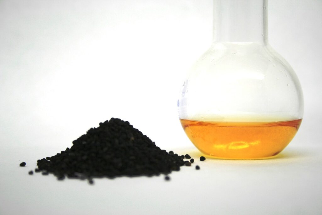 olio di semi neri di nigella dentro una brocca trasparente con semi accanto