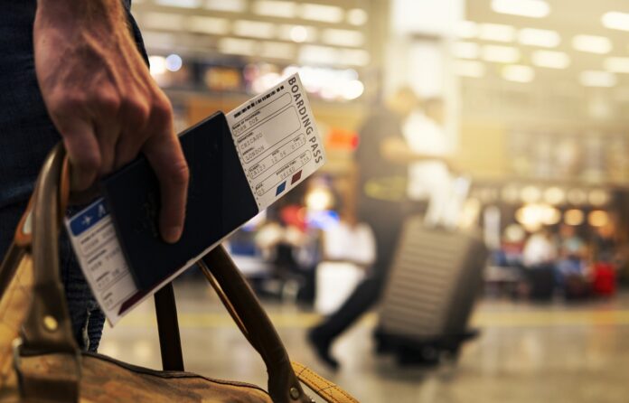 Fuga di cervelli - nella foto si vede in primo piano una mano che tiene un biglietto e la prersona è in un aeroporto