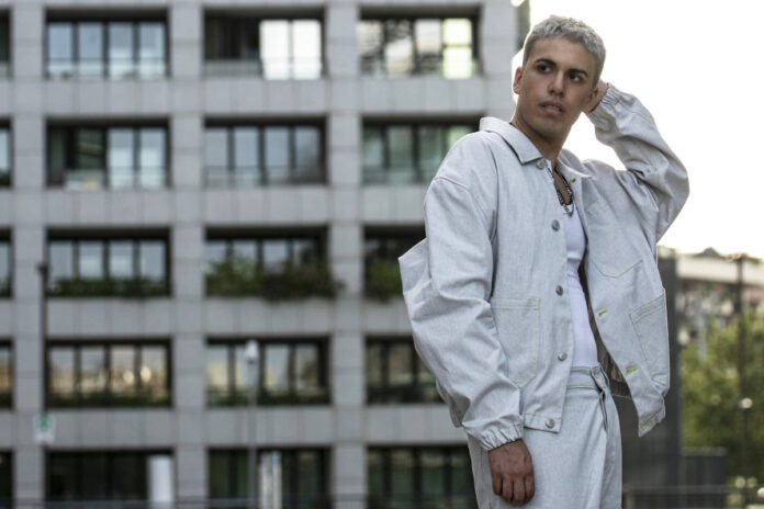 giovanni segreti bruno in primo piano, vestito completamente di bianco, sullo sfondo le rovine di un edificio