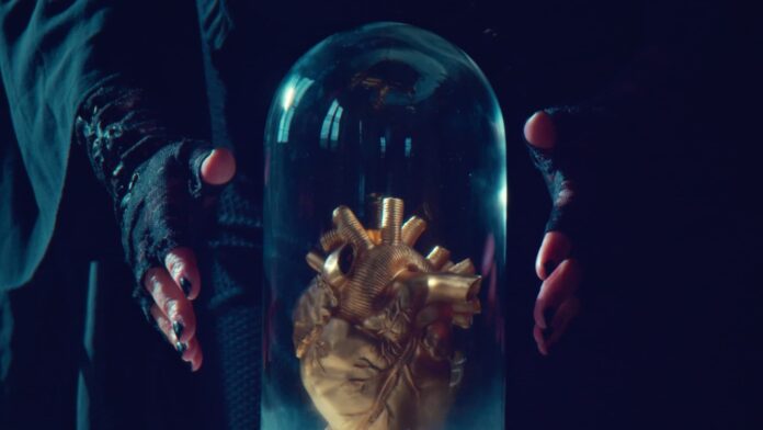 gipsy fiorucci - due mani guantate attorno a una teca di vetro che contiene un cuore dorato