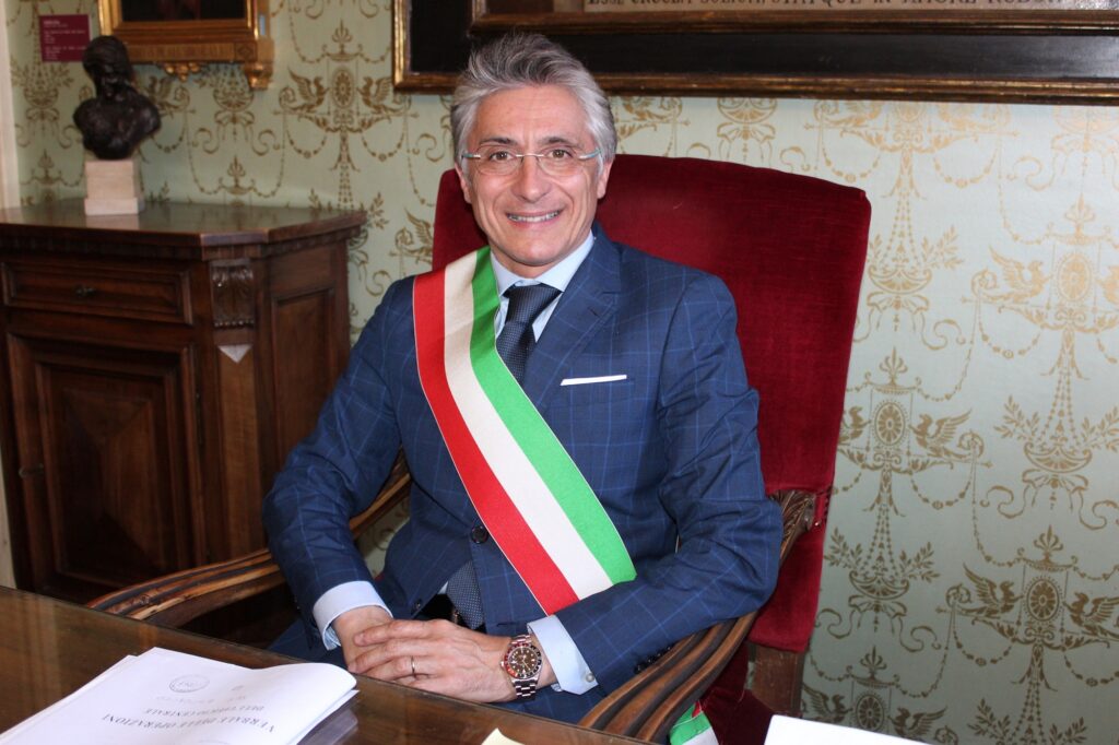 il sindaco di Alba Carlo Bo con la fascia tricol9ore seduto alla scrivania