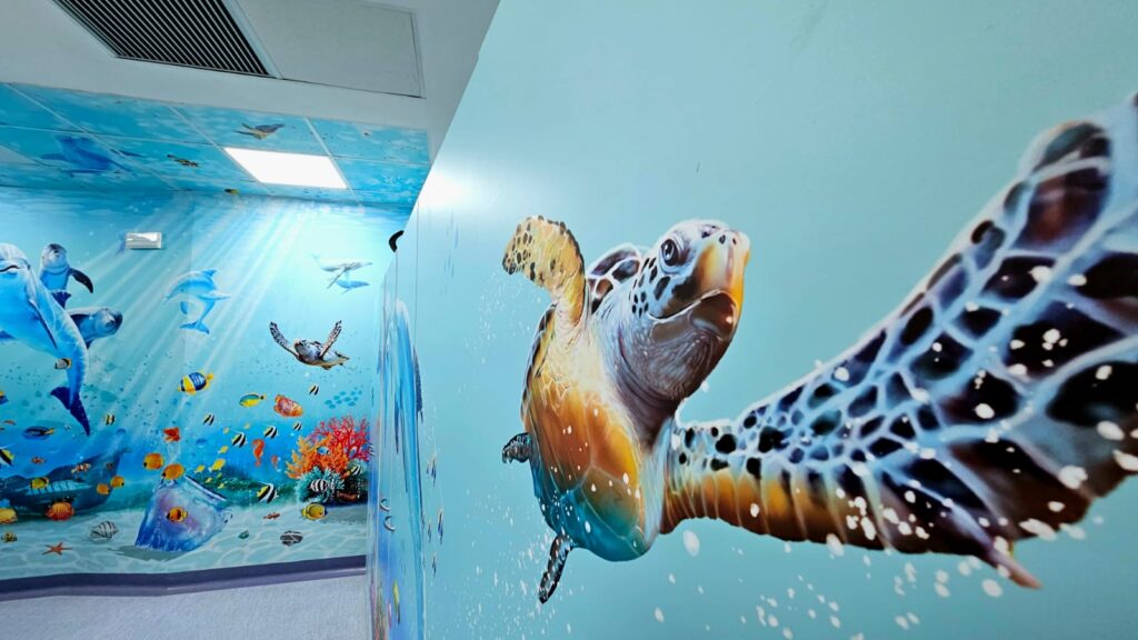 Ospedali dipinti - le pareti di un reparto ospedaliero dipinte diblu con coralli e un'enorme tartaruga