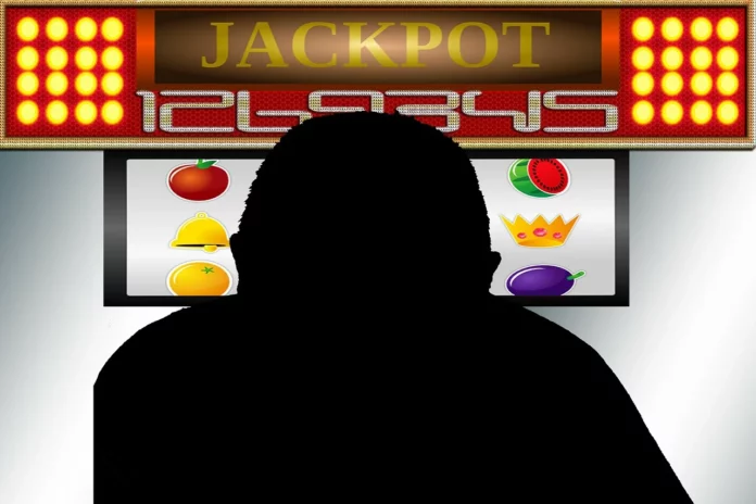Pubblicità del gioco d'azzardo ludopatia- una figura nera di un uomo davanti ad un pc dove sullo schermo c'è una slotmachine ocn la scritta 