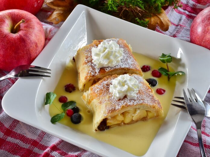 Trentino Alto Adige, in un piatto bianco quadrato un trancio di strudel di mele con dell acrema gialla e frutti di bosco