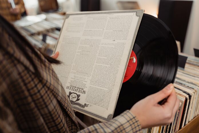 una persona tiene in mano la custodia dalla quale esce un disco in vinile con etichetta rossa