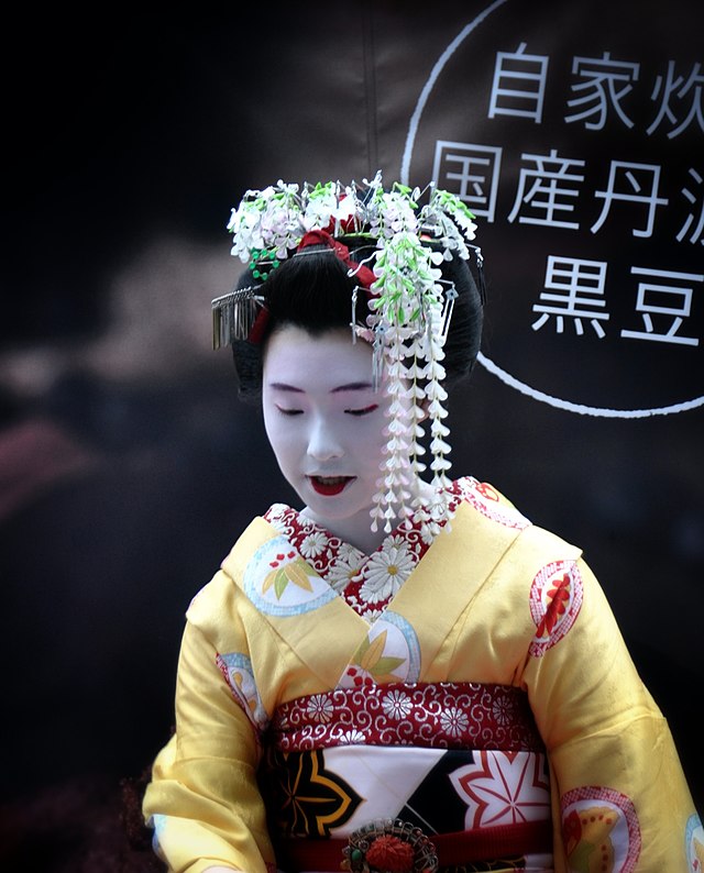 un donna con veste tradizinale kimono dorato e porpora 
Maiko - Flickr - xiffy.jpg