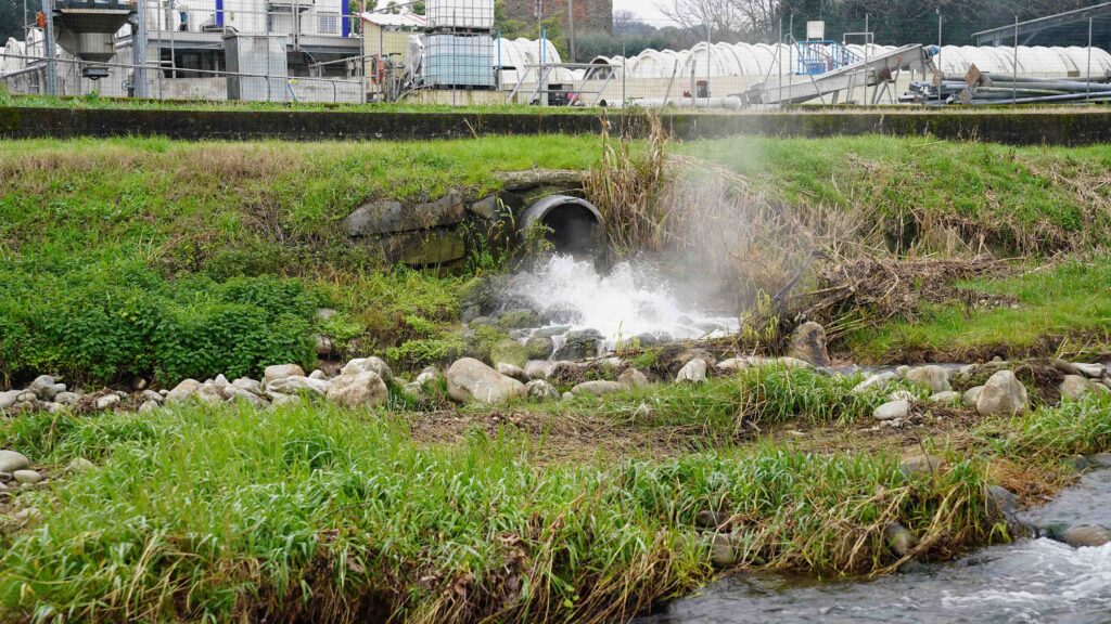 uno scarico fognario in mezzo alla campagna da cui fuoriesce acqua