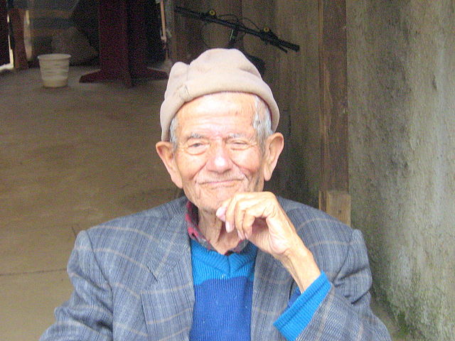 un umo anziano sorridente a mezzo busto con cappello in testa